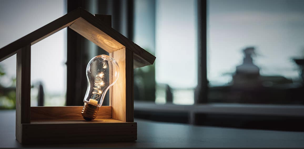 Light bulb with wood house on the table, a symbol for constructi