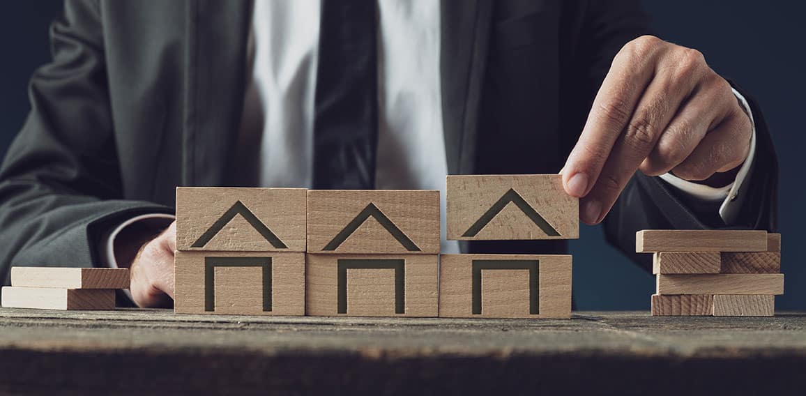 Realtor building houses of wooden blocks