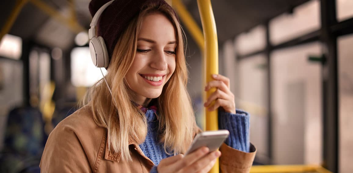 Young woman with headphones listening to music in public transpo