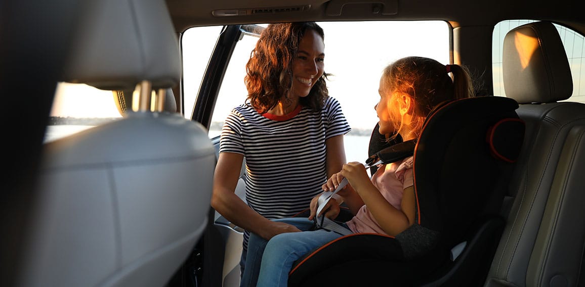 Woman fastening her daughter with car safety belt. Family vacati