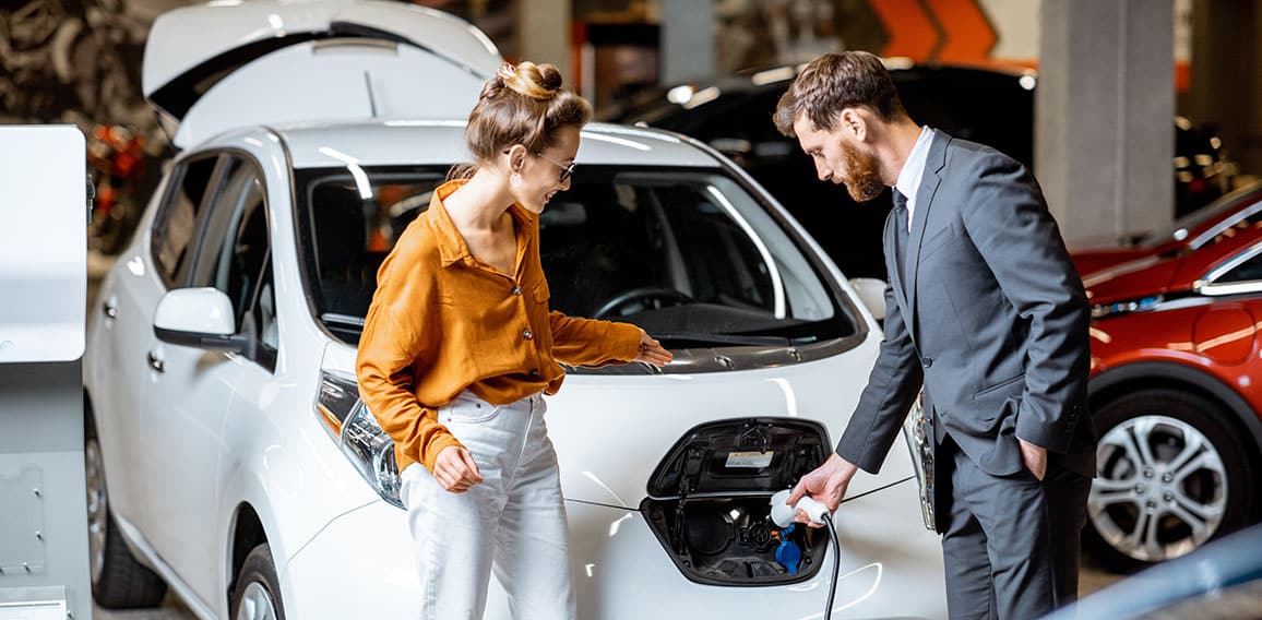 Sales manager with client near electric car at the car dealership