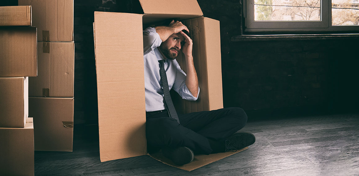 Businessman depressed for the failure of the company hidden in a cardboard box