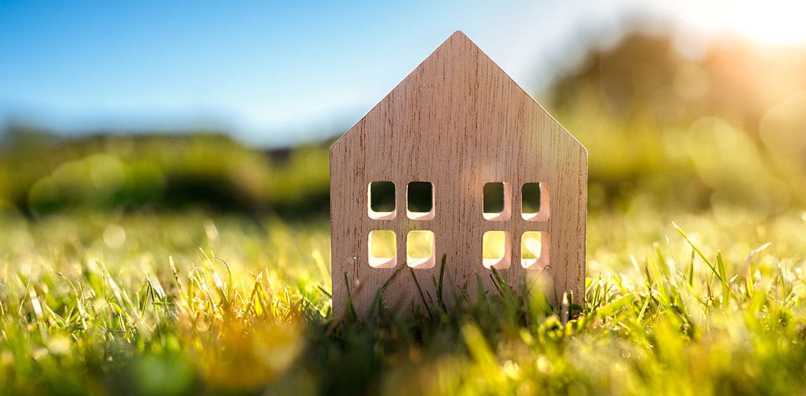 Ecological wood  model house in empty field at sunset