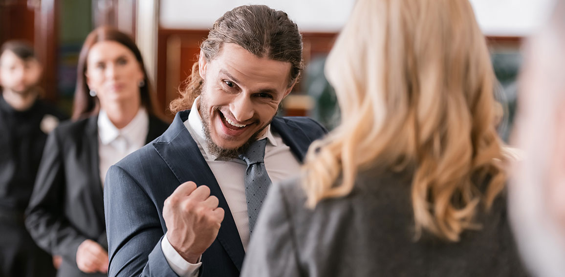 selective focus of excited businessman showing win gesture near advocate and prosecutor in court