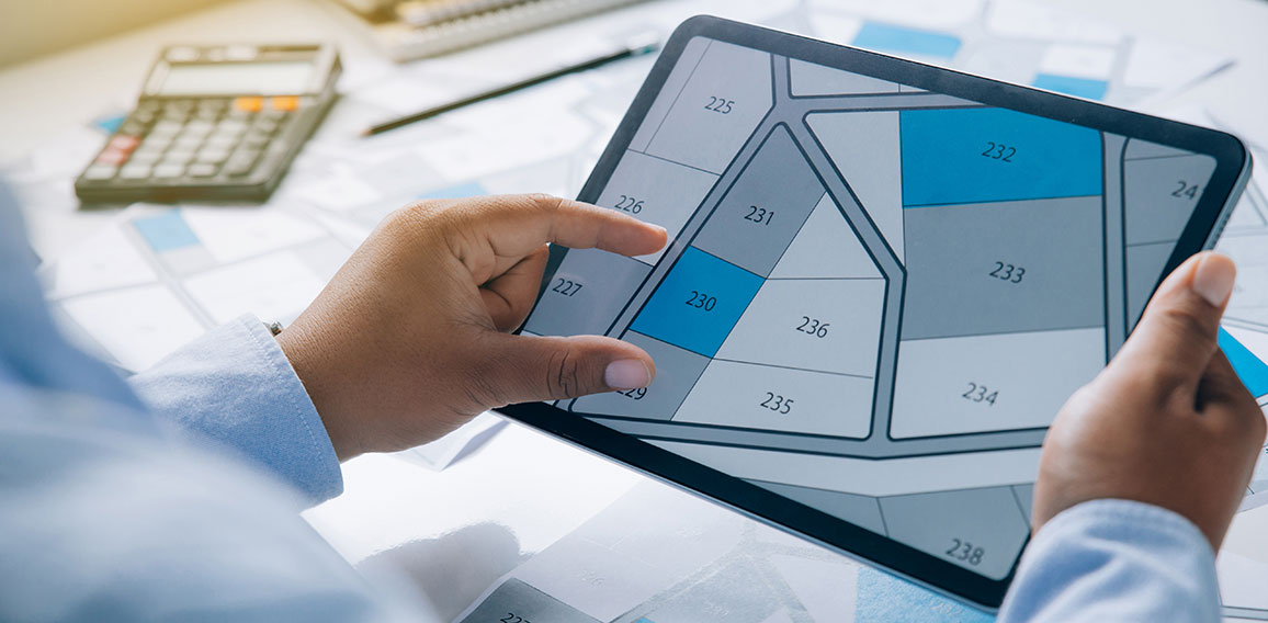 Man holding a tablet looking at lots of lands. Land plot managem