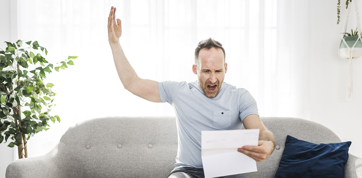 Shocked man holding some documents on sofa livingroom