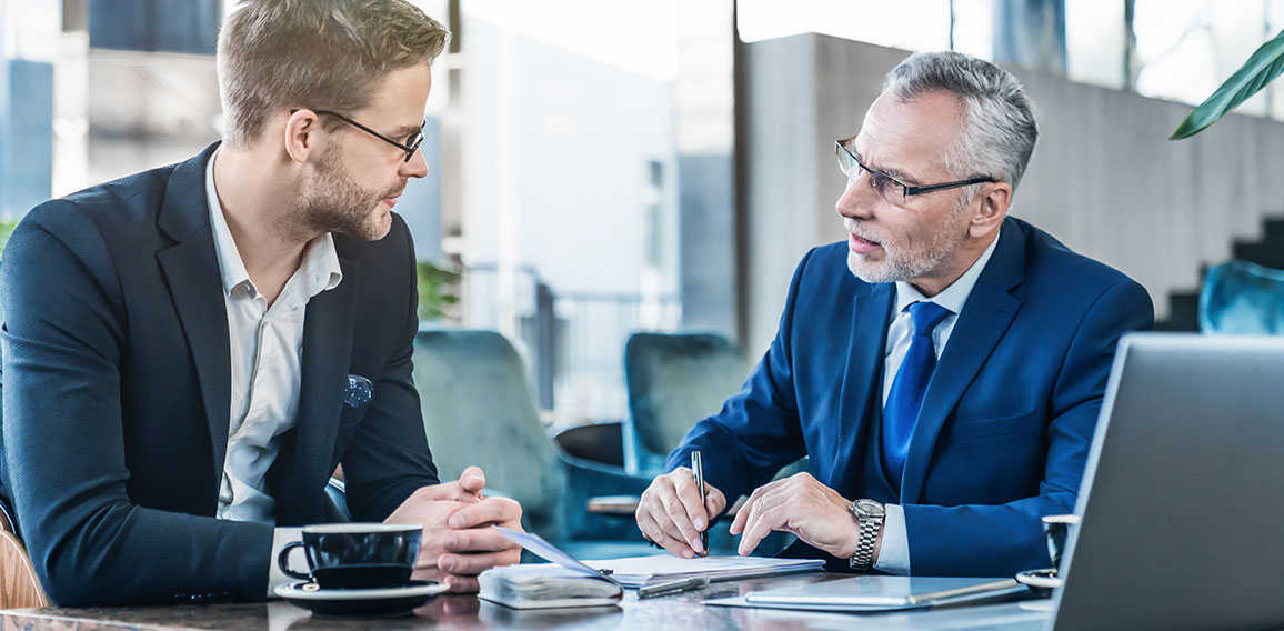 Horizontal shot of young executive showing his business proposal to a senior man sitting in foyer