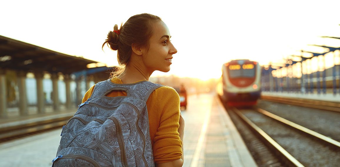 portrait of a young woman traveler with small backpack on the railway stantion