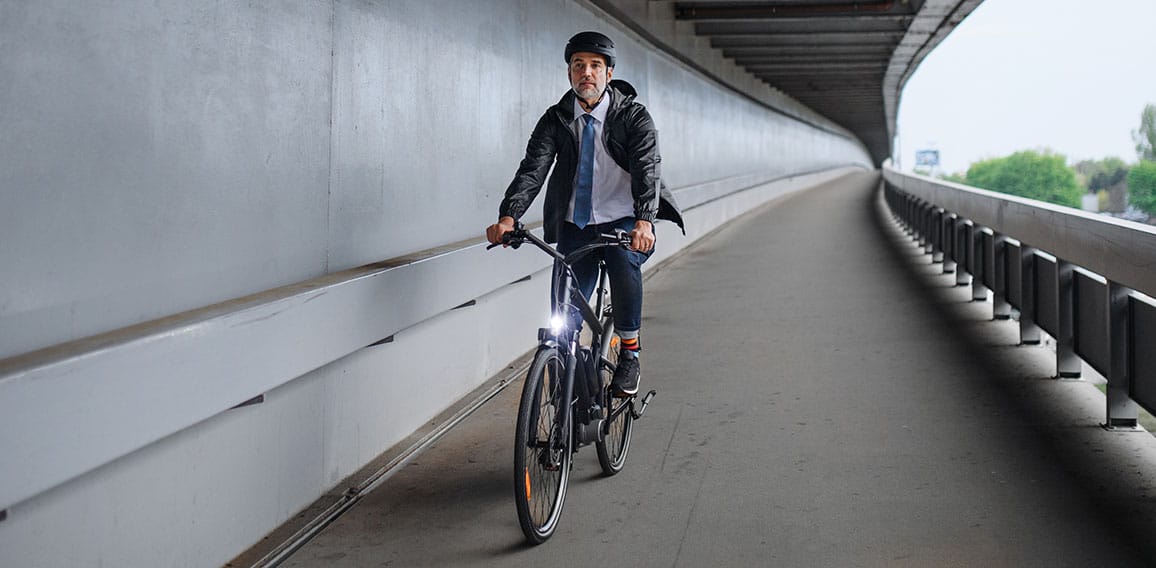 Businessman commuter on the way to work, riding bike over bridge, sustainable lifestyle concept.