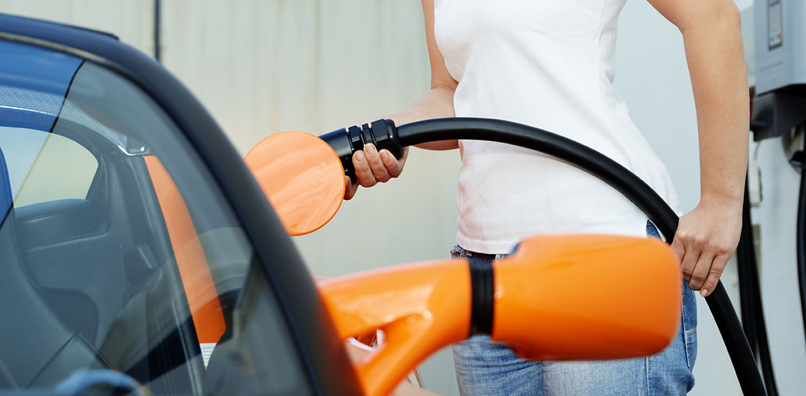 Pretty woman is loading electrically powered car outdoors