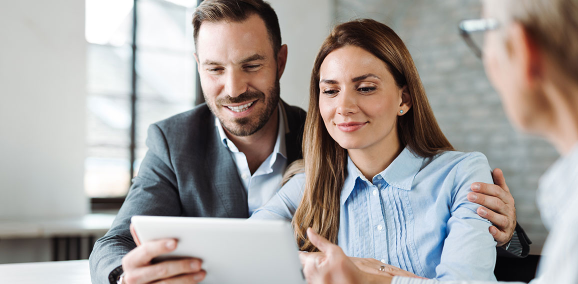 Happy couple using digital tablet on a meeting with insurance ag