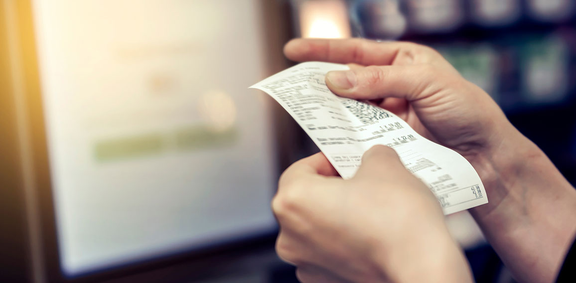 the girl looks at the receipt in the store