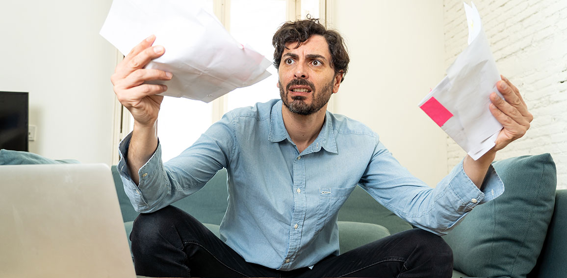 angry man paying bills as home with laptop and calculator