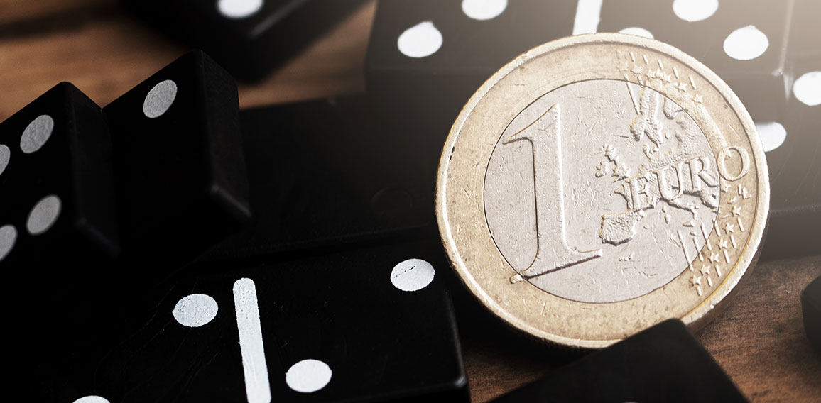 Shiny one euro coin lying on top of spilled domino tiles.