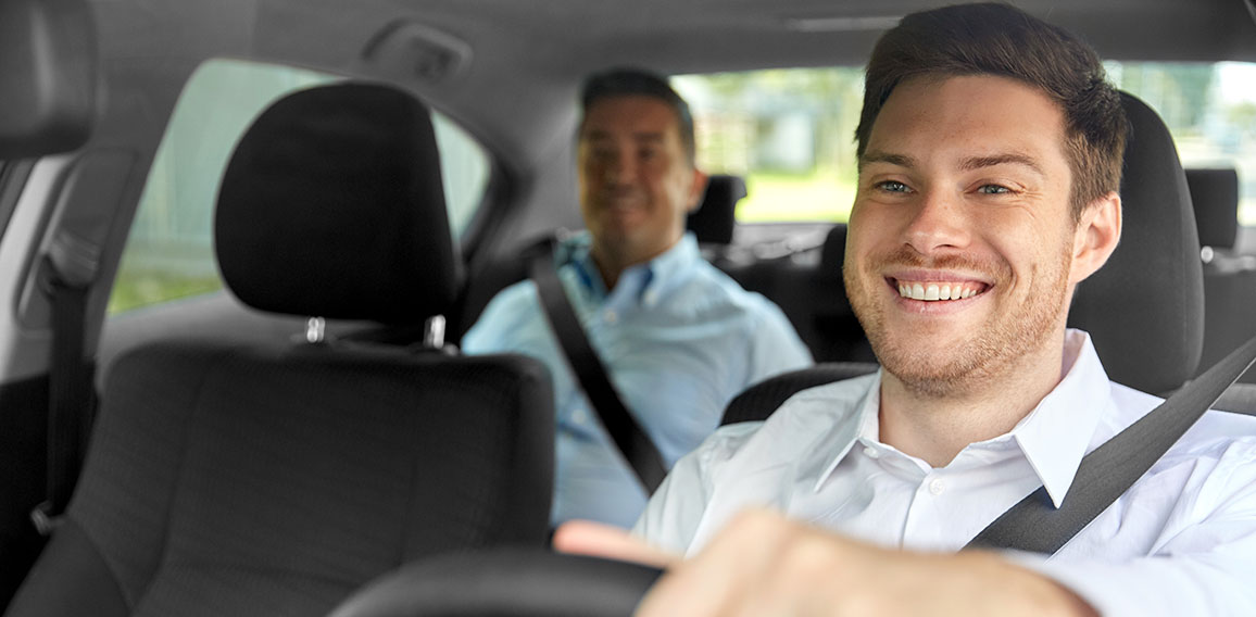 male taxi driver driving car with passenger