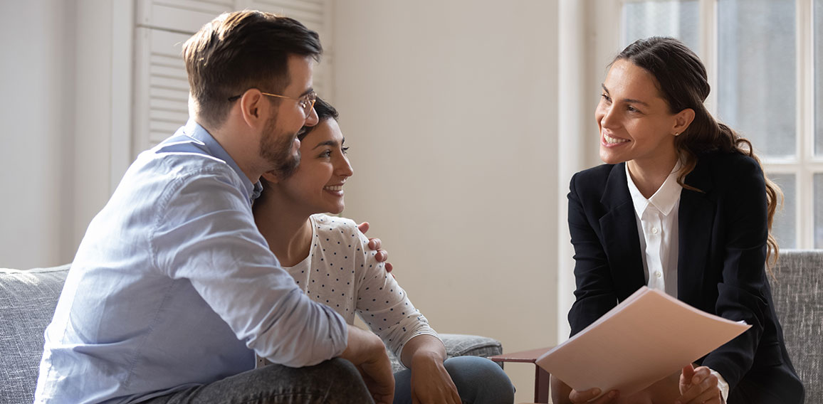 Client and banker seated on sofa discuss mortgage contract terms