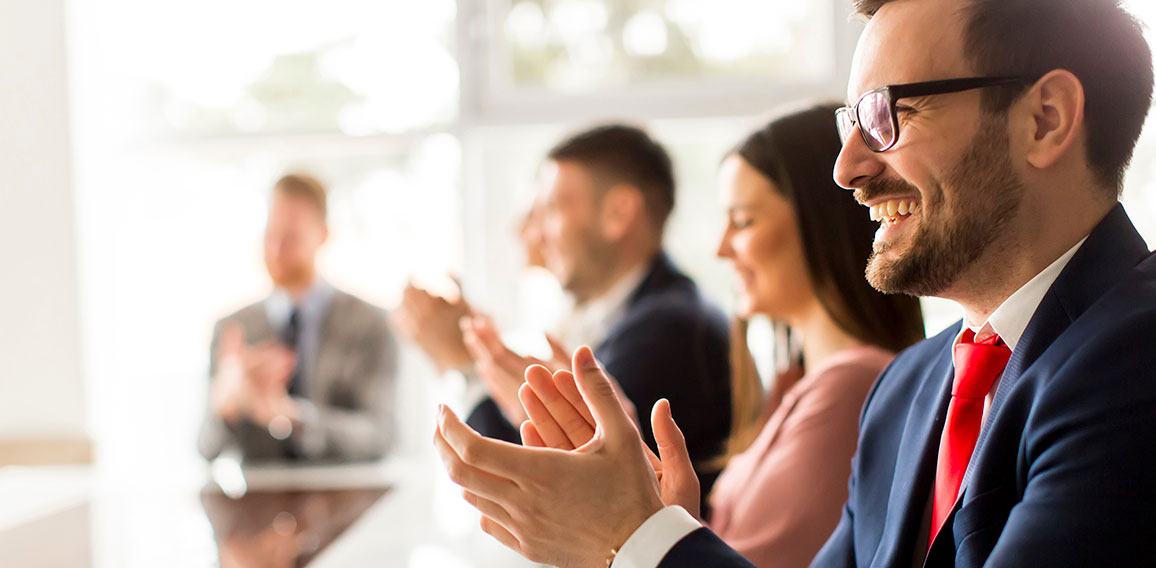 Smiling business group clapping hands at the meeting