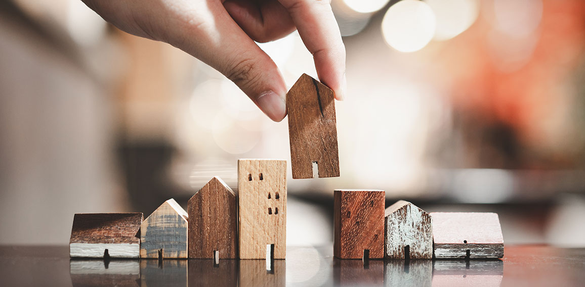 Hand choosing mini wood house model from model on wood table, se