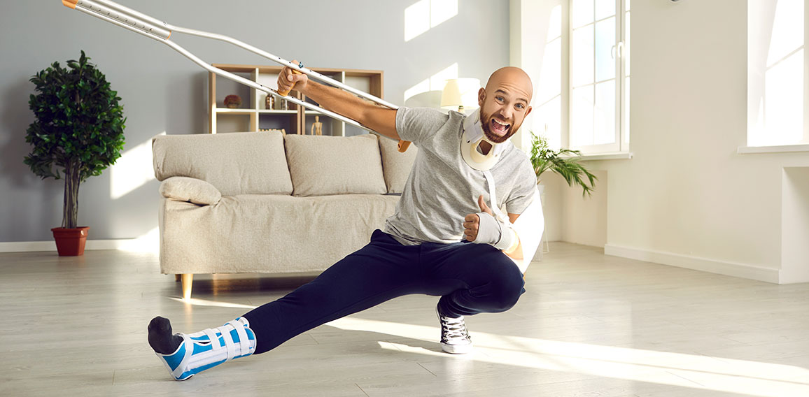 Happy man who's on sick leave due to his injuries is holding crutch and showing thumbs-up