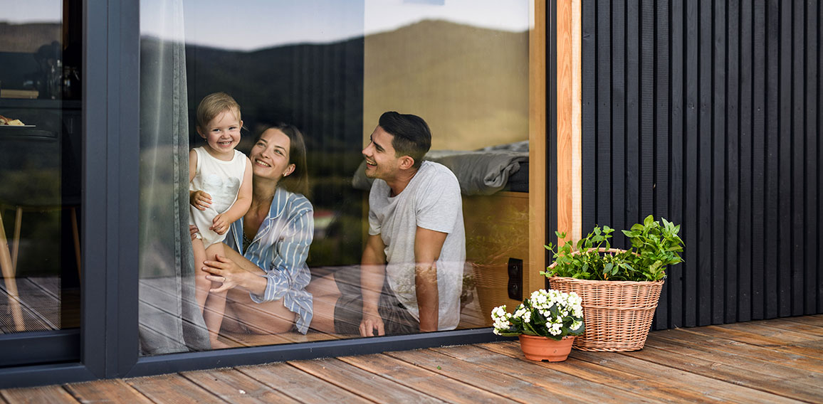 Young family with small daughter indoors, weekend away in container house in countryside.