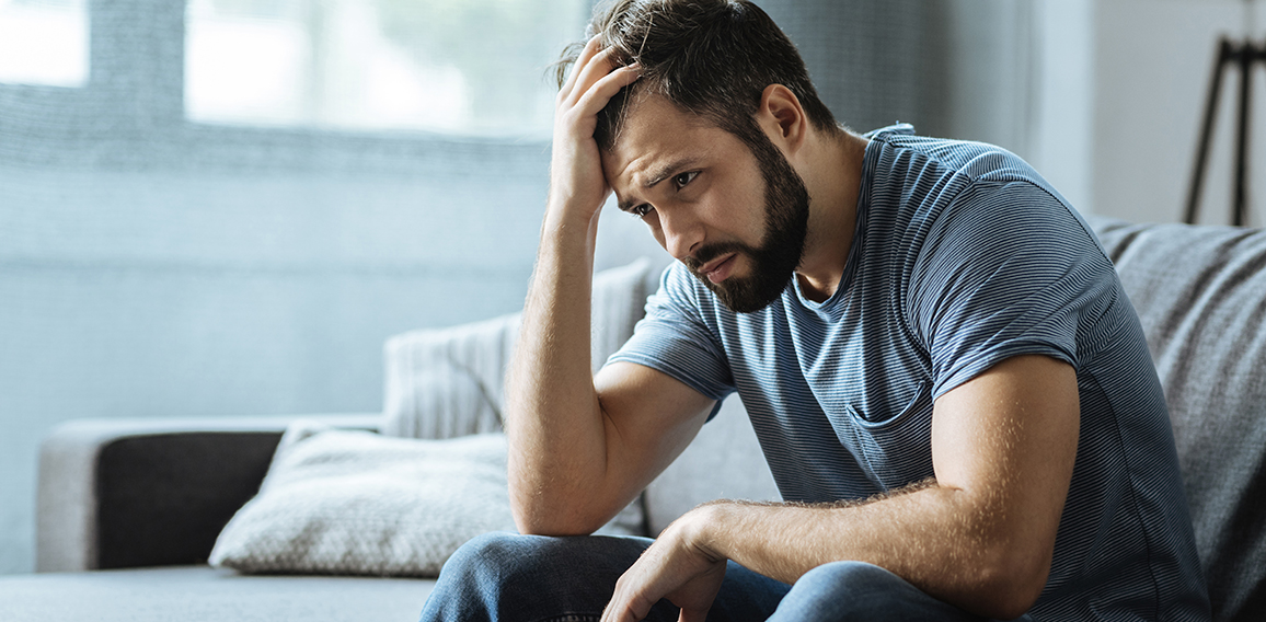 Sad gloomy man holding his forehead