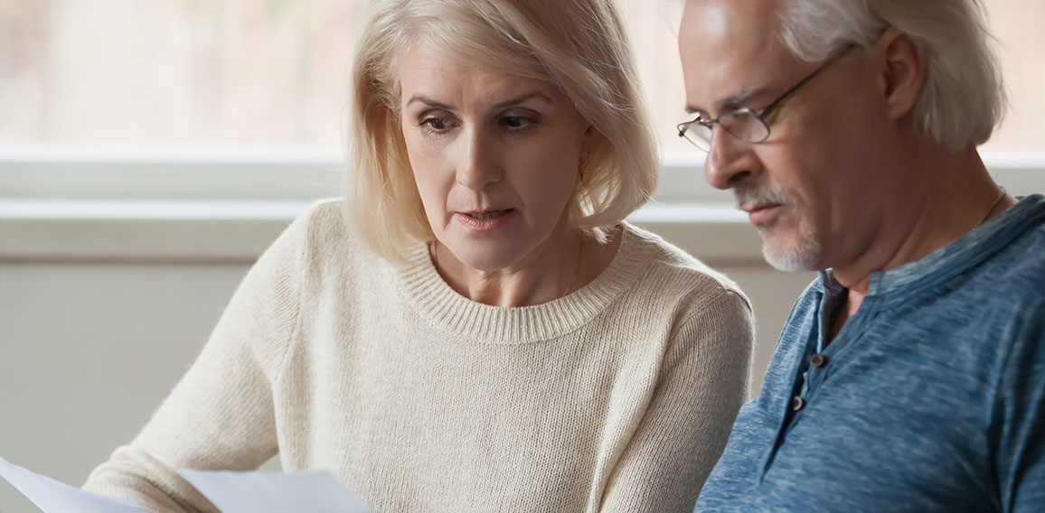 Aged couple read bank statement analyzing family expenses feels concerned