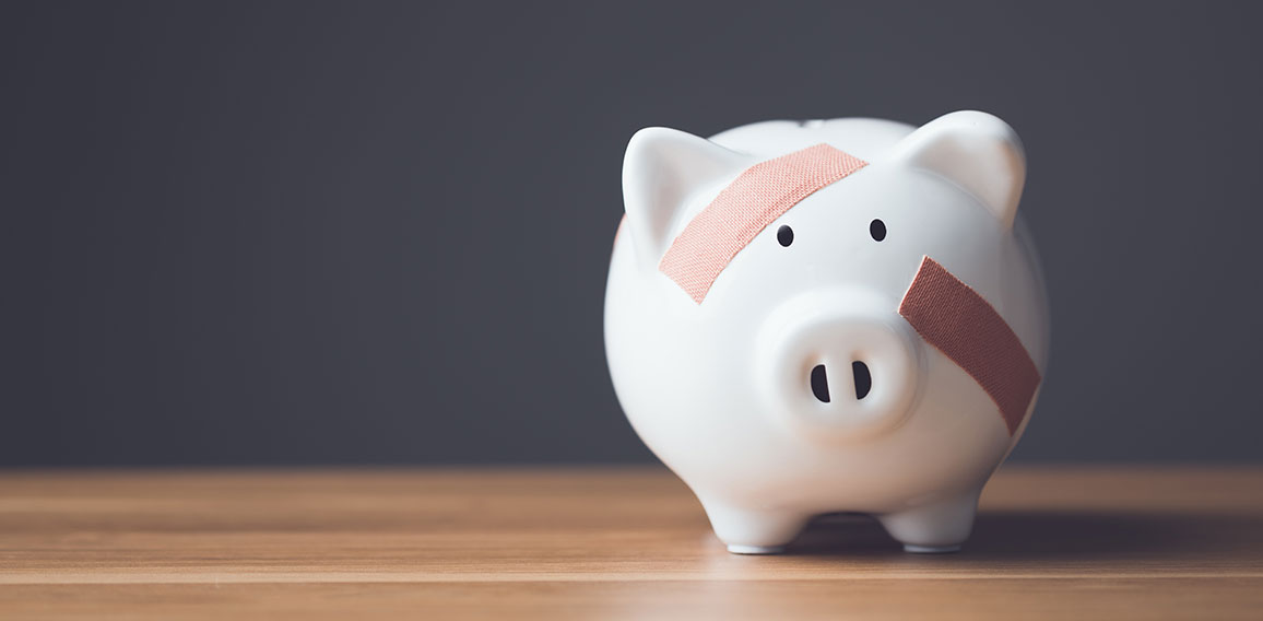 Financial problem, Bankrupt or fail in business concept. White piggy bank with plastic adhesive bandages on wooden desk with dark copy space wall background. Fail, Bankrupt or unsuccessful idea.