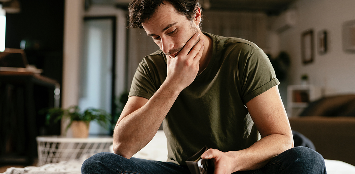 Young man checking empty wallet, no money. Unemployed sad man si