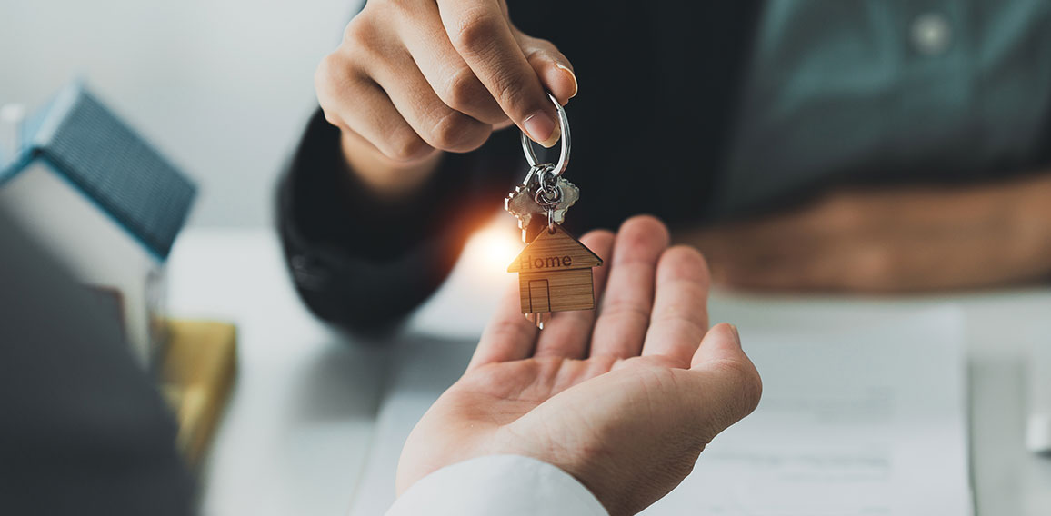 Close up Business woman or Real Estate agent giving house key after signing agreement for buying house. Bank manager and real estate concept.