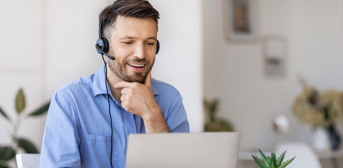 Business Education. Handsome businessman in headset watching webinar on laptop in office