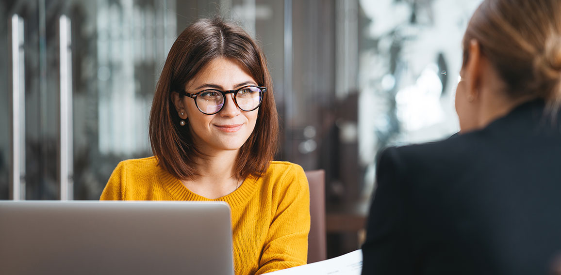 Group of happy business people have meeting at workplace in office. Two positive woman working together using modern laptop for working concept