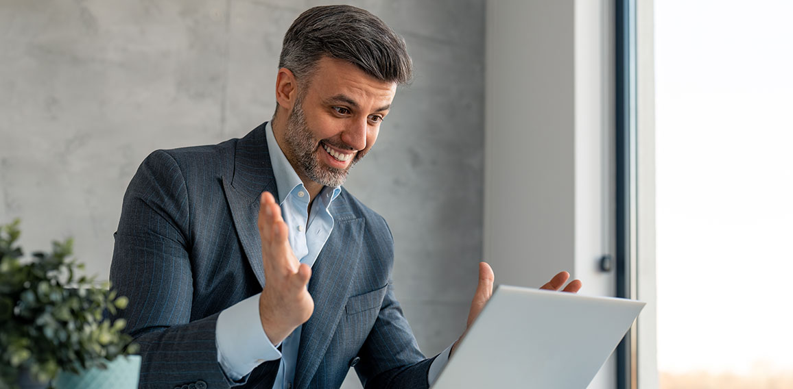 Happy confident businessman video calling on laptop, working in