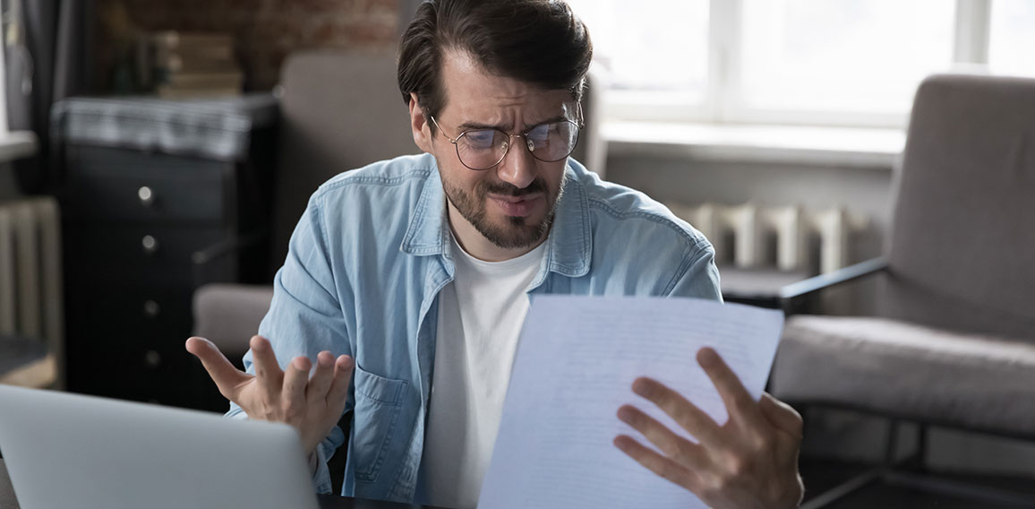 Annoyed frustrated entrepreneur looking at paper report with bad news