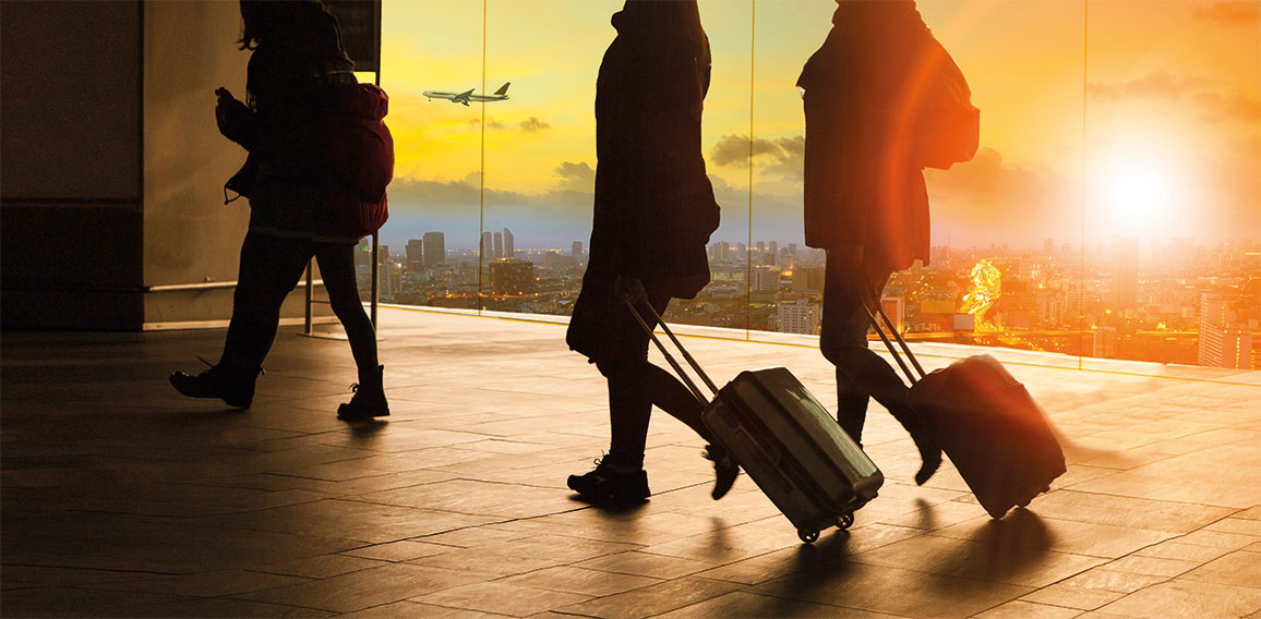 people and traveling luggage walking in airport terminal building with sun set sky at urban scene and air plane flying background