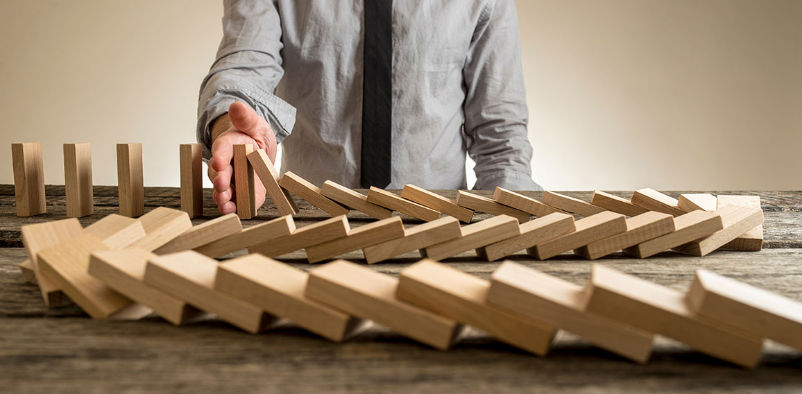 Hand stopping domino effect of wooden blocks