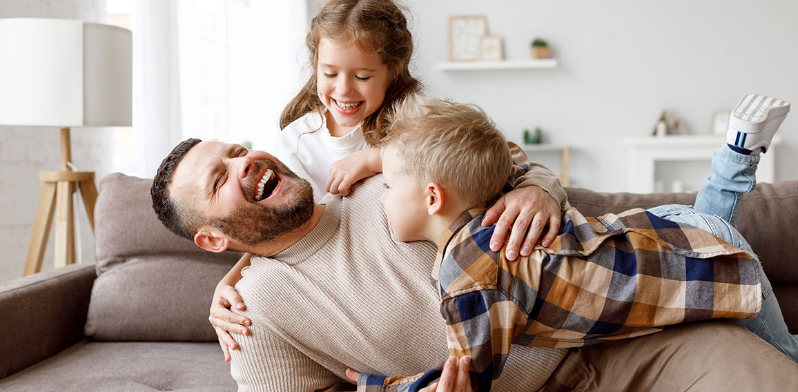 Kids playing with father on sofa