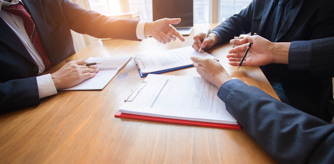 business people and lawyers discussing contract papers sitting a