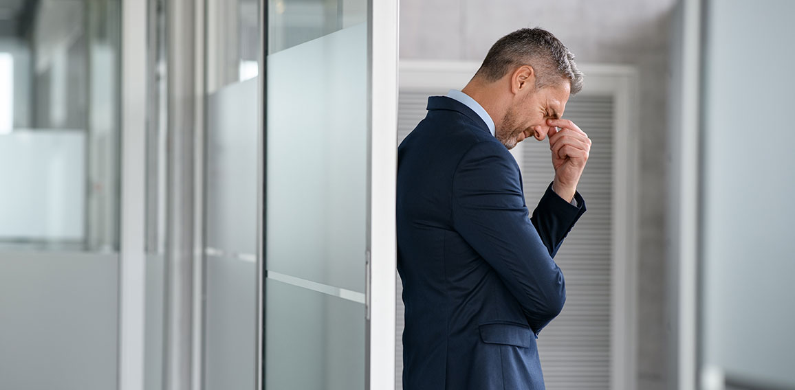 Stressed businessman suffering headache in office