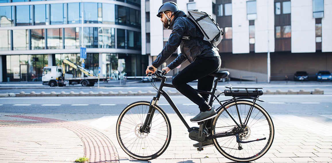 Male courier with bicycle delivering packages in city. Copy space.