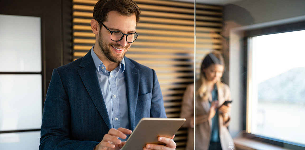 Happy professional successful business man using tablet and working in office