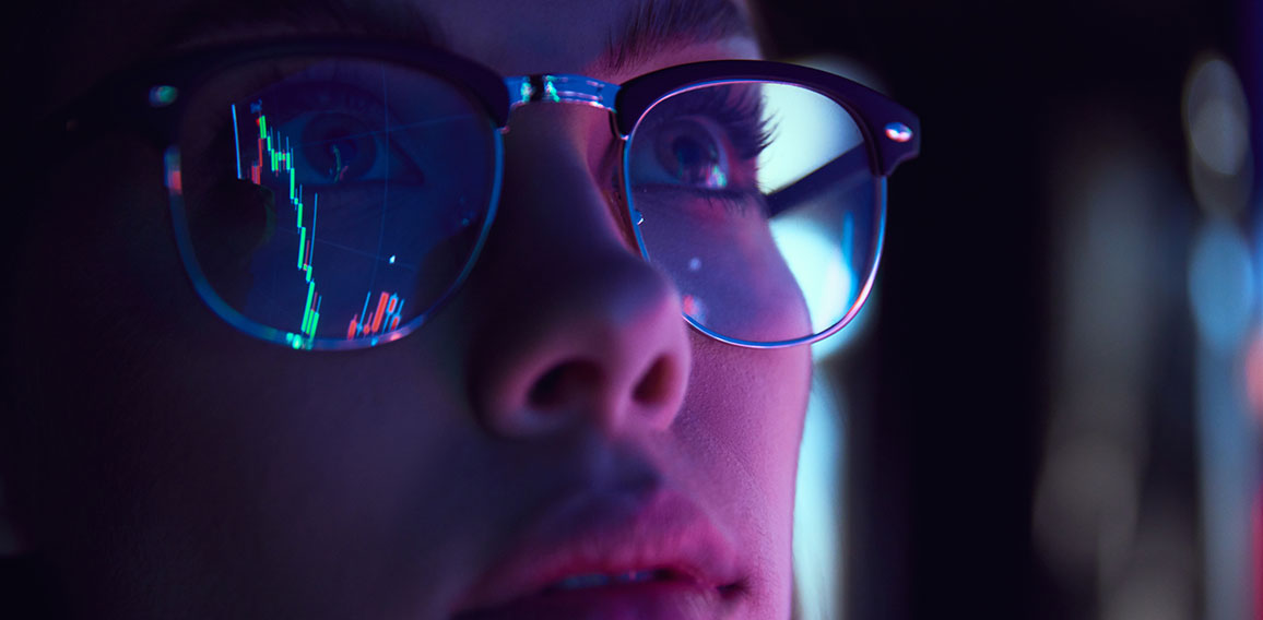 Close up view of girl's eyes in glasses looking at pc screen with computer reflection at eyewear. Using internet, working online. Technology, AI, business