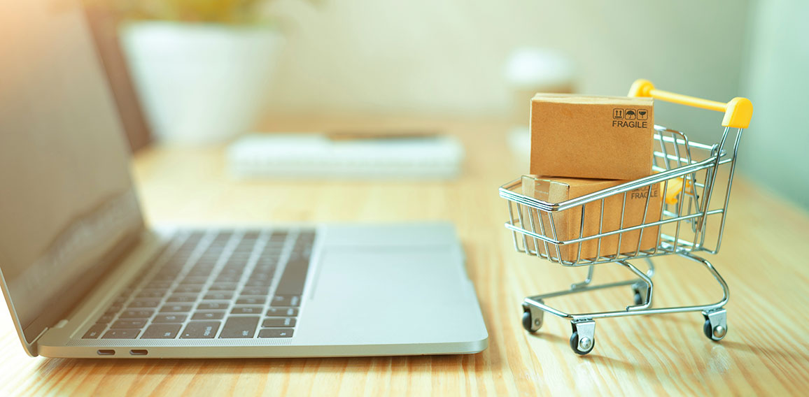 Brown paper boxs in a shopping cart with laptop keyboard on wood