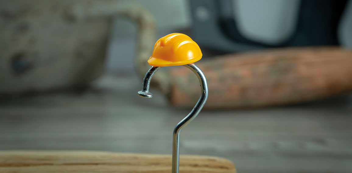 Carpentry nail shaped as question mark and helmet