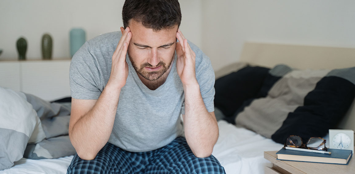 Restless man waking up early with headache after rough night