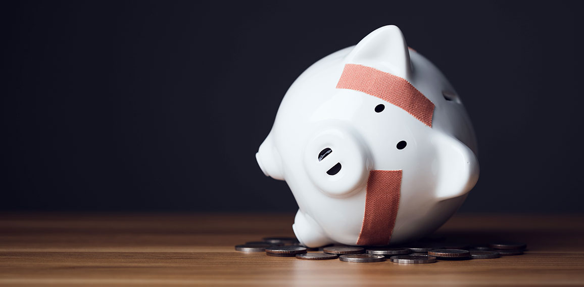 Financial problem, Bankrupt or fail in business concept. White piggy bank with plastic adhesive bandages on wooden desk with dark copy space wall background. Fail, Bankrupt or unsuccessful idea.