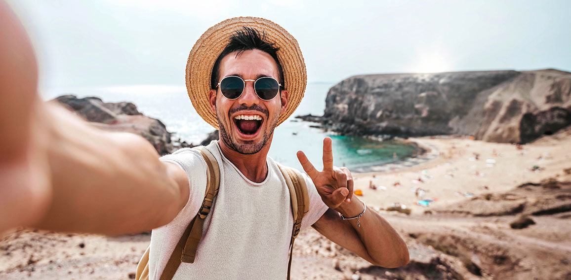 Handsome man wearing hat and sunglasses taking selfie picture on