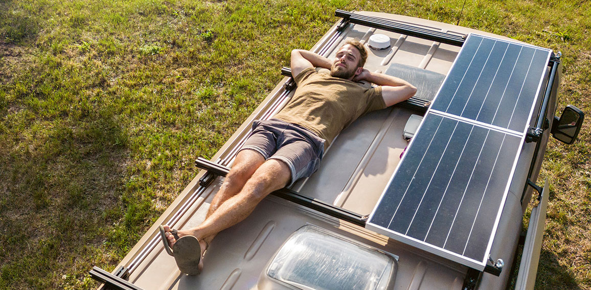 Man relaxing on the roof of a camper van