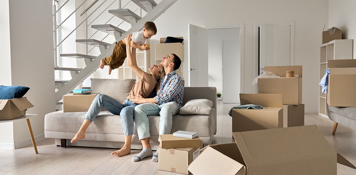 Happy young family playing with kid son together in new home on moving day.