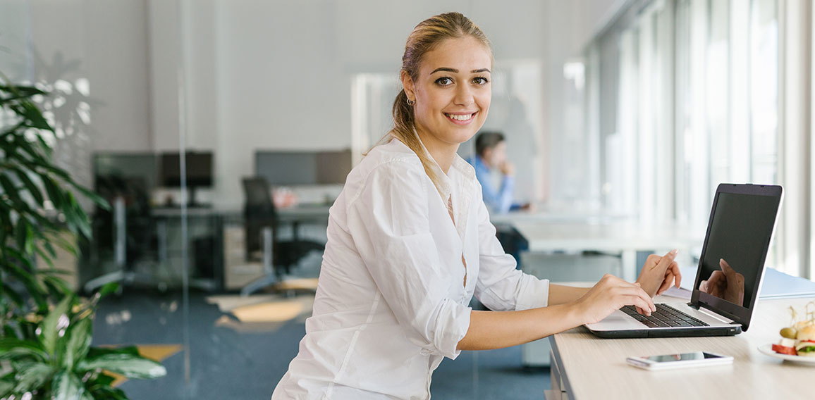 Business woman working on laptop in office while sitting on pila