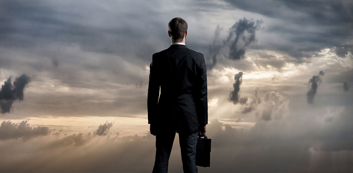 Businessman with briefcase standing over dark, dramatic ocean ba